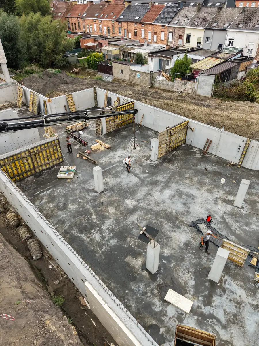 Luchtfoto van een bouwput met betonnen kelderwanden en bekisting